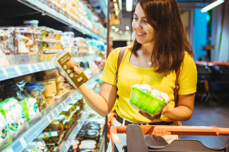 Female grocery store customer taking advantage of a cross-promotional marketing offer on a package of mushrooms.